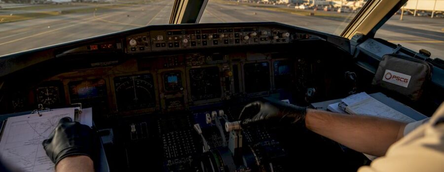 Hands adjusting airplane cockpit instruments with PSCG logo