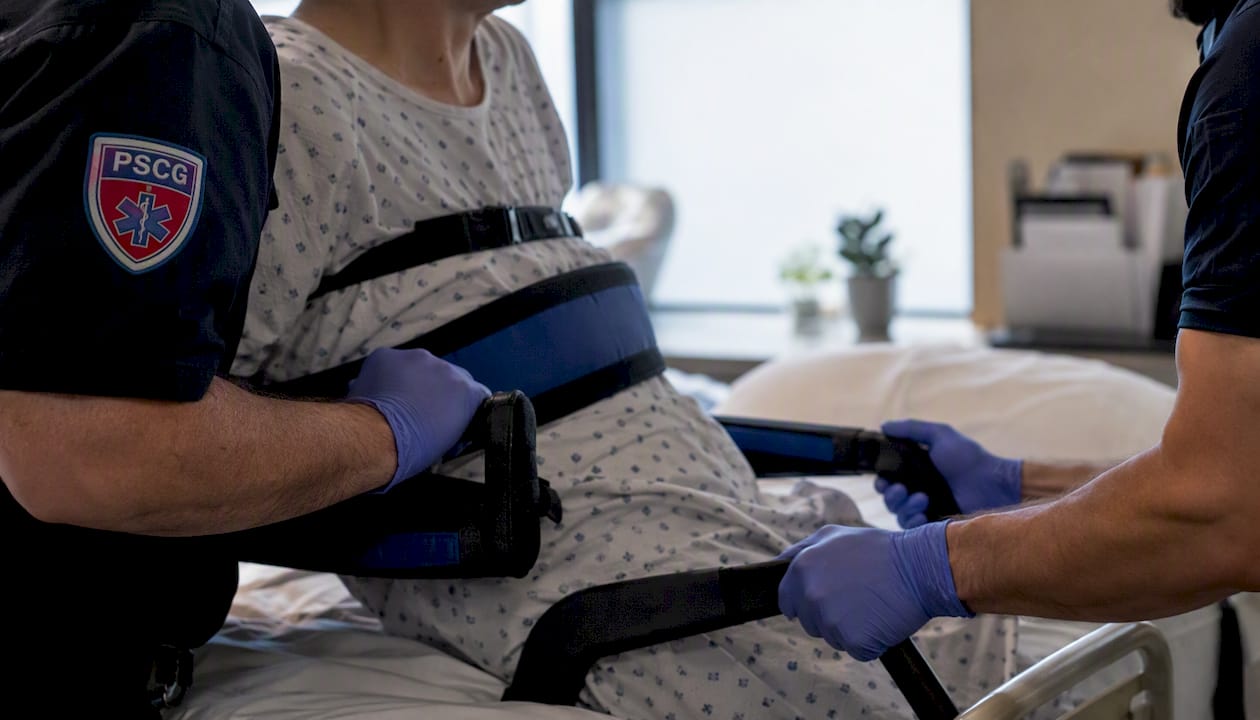EMS providers assisting patient from bed to sitting